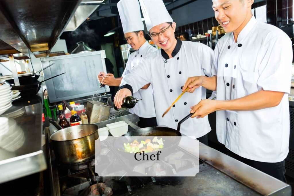 A chef plating a dish in a busy restaurant kitchen.